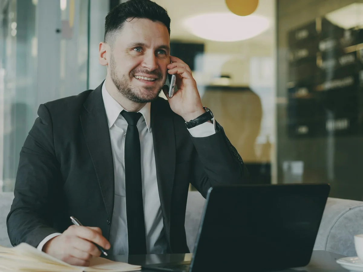 Professional taking a phone call beside a laptop