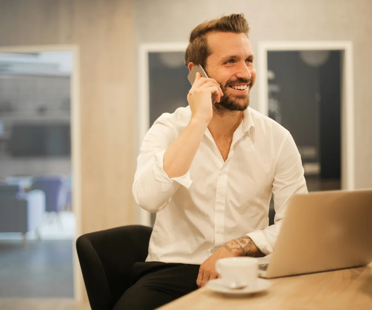 Professional taking a phone call beside a laptop
